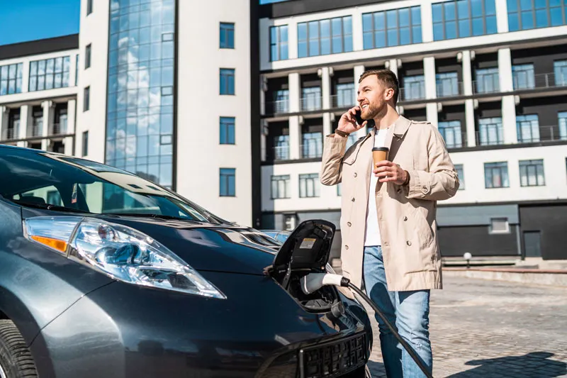 Collaborateur d'entreprise rechargeant sa voiture électrique sur une borne du parking de l'entreprise